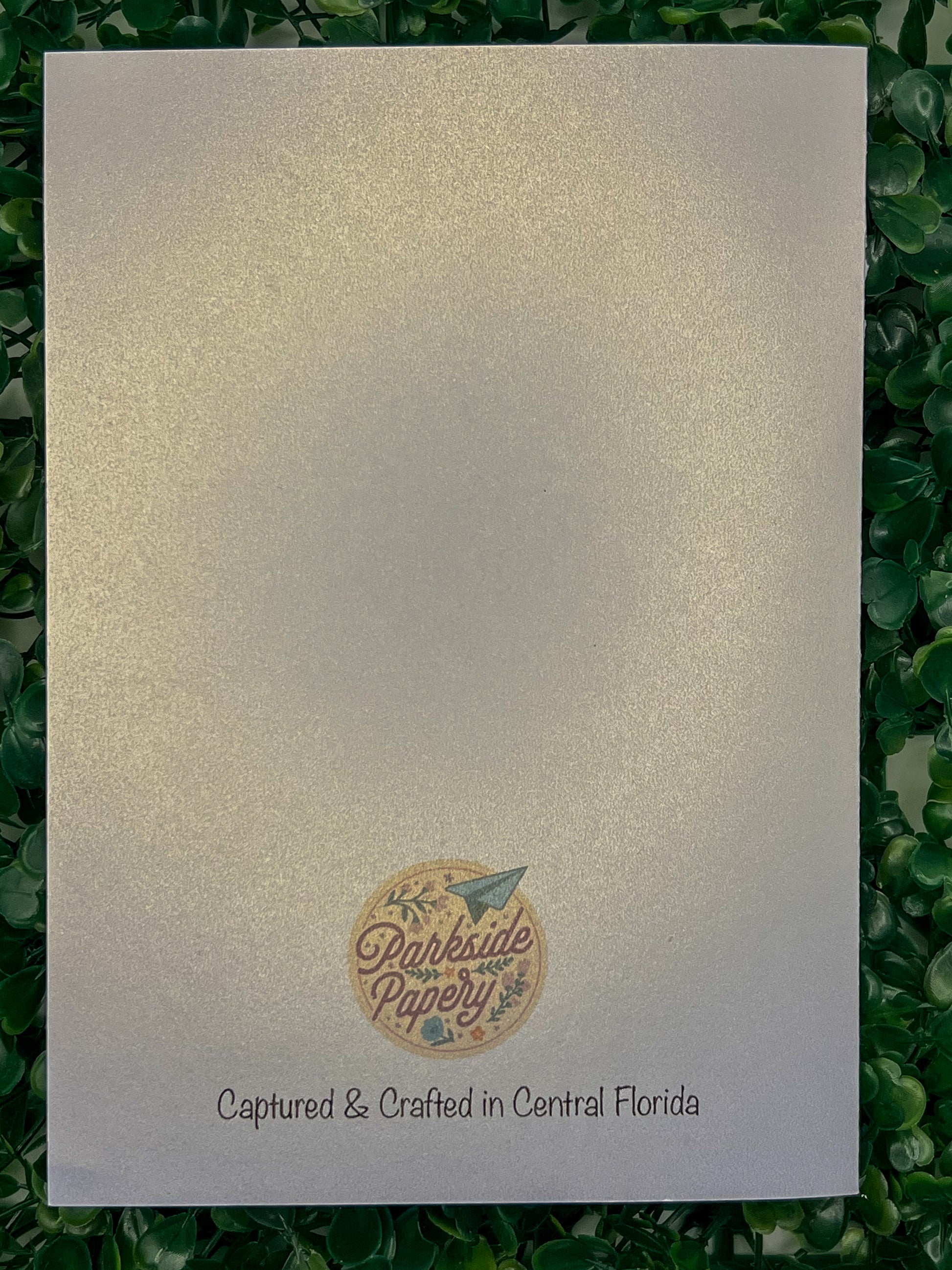 White card with a circular logo and text on a green leafy background